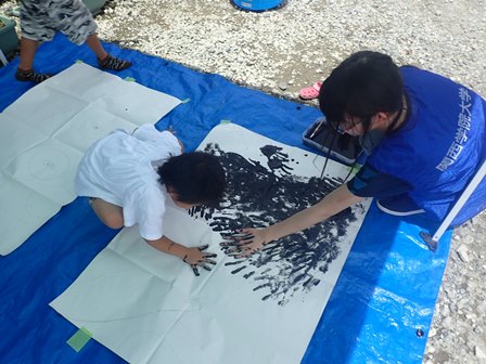 手形アートを作る学生と子ども