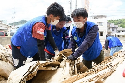 被災した工場から資材を搬出する学生