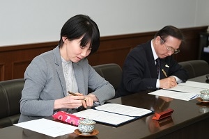 協定書に署名する吉岡理事長と村田学長