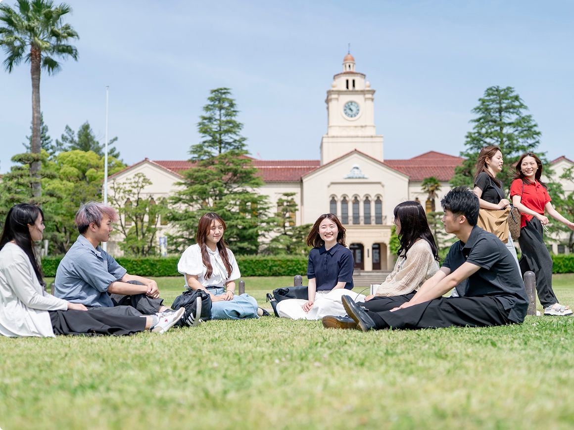 芝生で語らう大学生たちの画像
